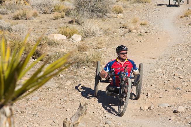 John Masson, a U.S. Army Special Forces Veteran, navigates through Blue Diamond on a 3-wheel hand-powered mountain bike, built by Bill Lasher of Las Vegas, during the Ride 2 Recovery Las Vegas Mountain Bike Challenge Monday, Jan. 27, 2014. Masson, who lost 3 limbs during a roadside bomb attack in Afghanistan in Oct. of 2010, is among many wounded veterans who are being helped by Ride 2 Recovery, a nonprofit organization that provides rehabilitation to injured veterans through cycling.